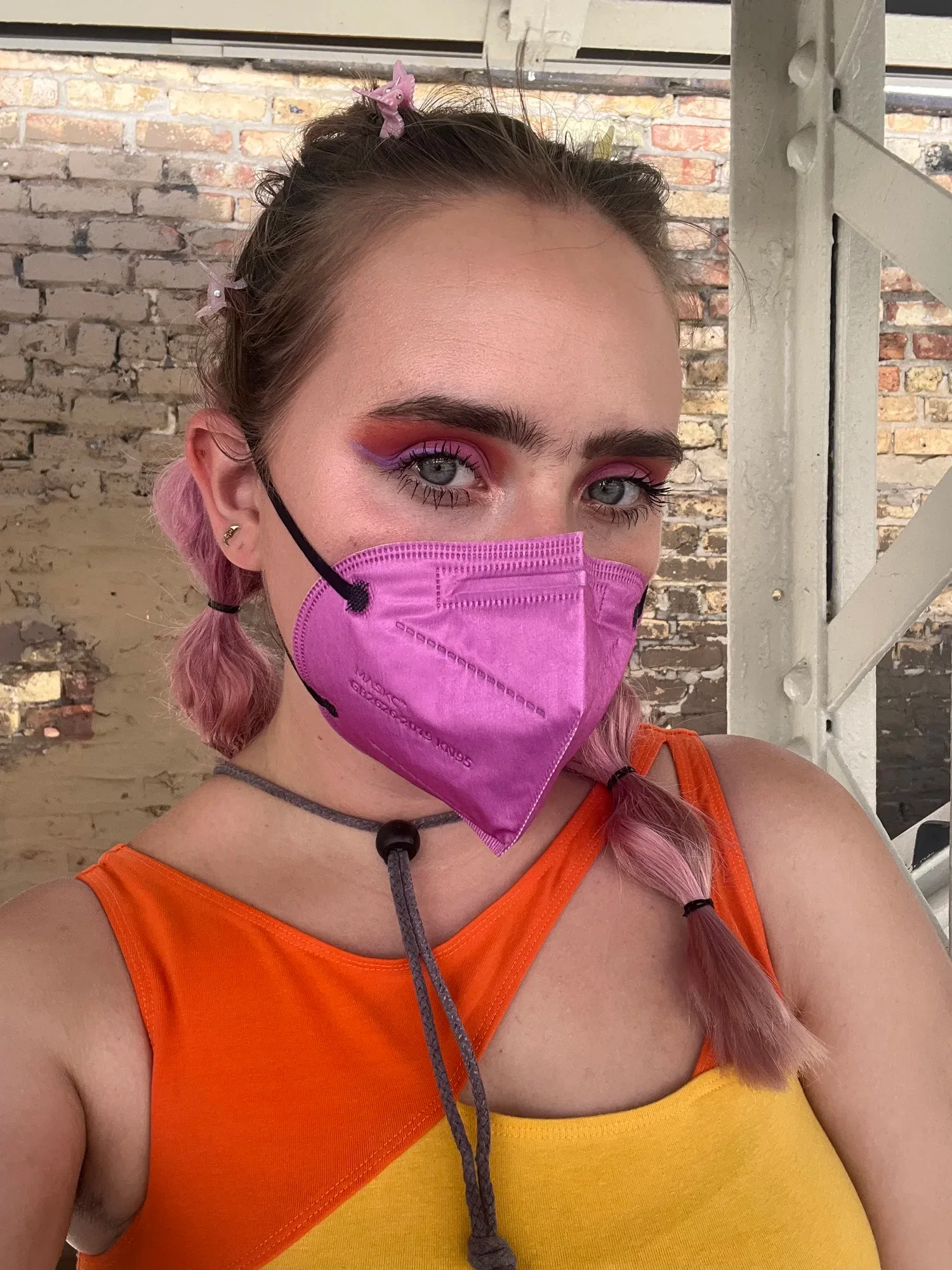 A young woman is wearing bright, colourful clothing with a matching mask. She looks like she’s about to go out and socialise.