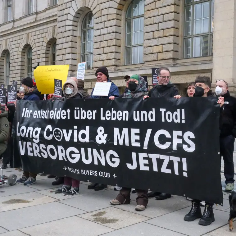 Crowd outside the Berlin parliament behind a banner: Long Covid & ME/CFS Versorgung jetzt!