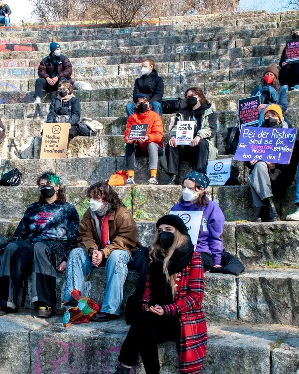 Protesters with signs sitting on the steps of the Mauerpark amphitheatre